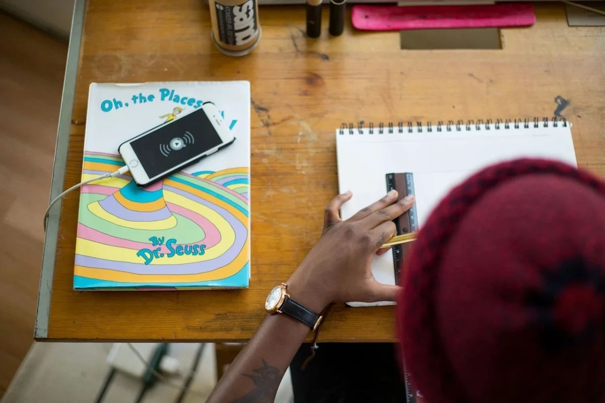 A person sketching a website wireframe on a notepad, representing the planning phase for mobile app.