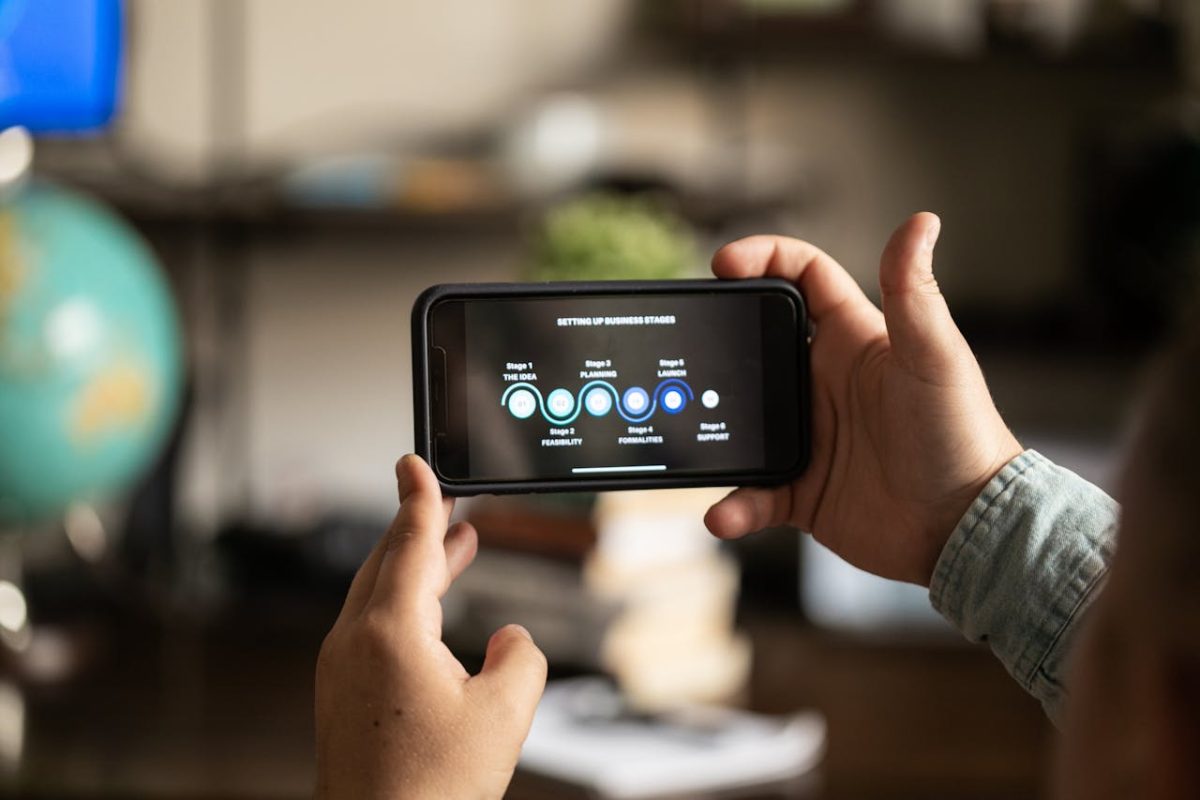 A person holding a smartphone displaying business planning stages, showcasing a user interface design.