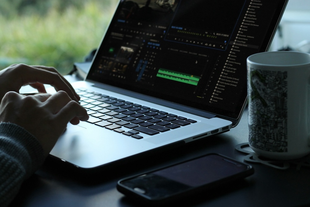 Close-up of a person editing video on a laptop with a dark mode interface, focused on user-friendly and visually appealing dark themes.